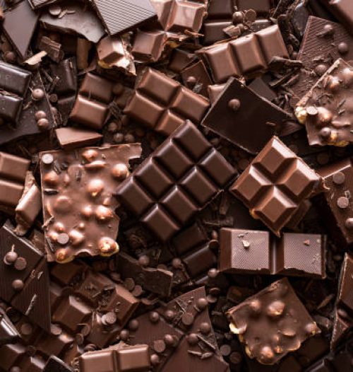 Assorted chocolate bar and chunks, background. Flat lay with a multitude of chocolate kinds. Delicious cocoa dessert. Baking chocolate collection.